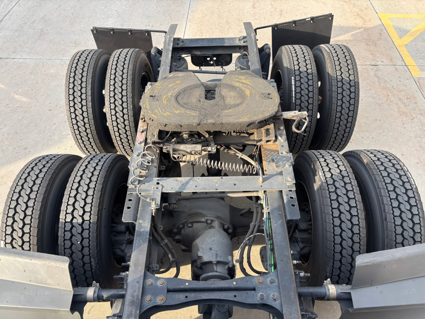 Rear view of a Freightliner PT126064ST truck chassis showing dual rear axles with six wheels, frame rails, drivetrain, and suspension components.