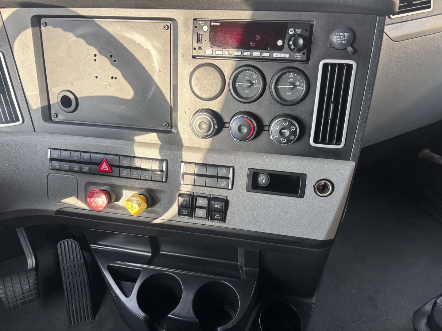 Truck dash with gauges, vents, control buttons, and cup holders; visible text includes various dials and a radio head unit