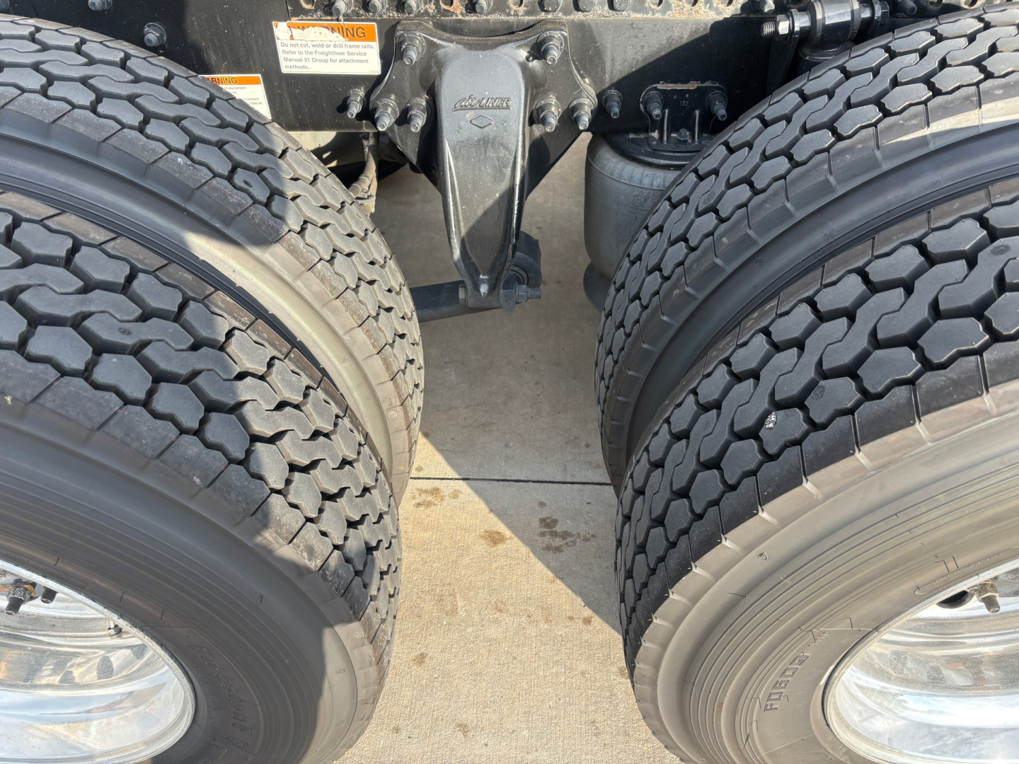 Freightliner PT126064ST drivetrain area showing dual rear axles and suspension components with tires.
