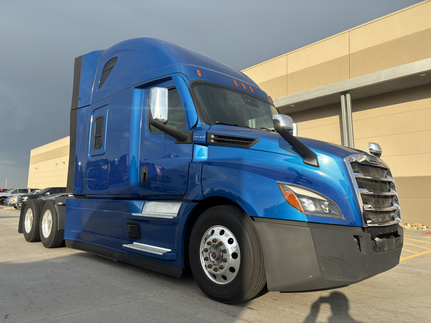Truck image: blue Freightliner PT126064ST conventional sleeper tractor, side view showing cab, front grille, and dual rear axles.