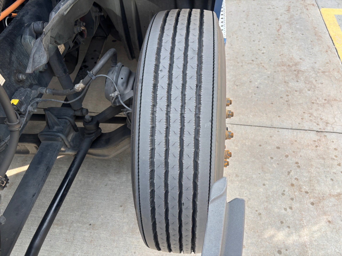 Front dual-axle truck wheel/view of tire with label details and suspension components; no legible stickers visible in this crop.
