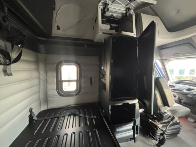 Interior view of a Freightliner PT126064ST cab with a partition and storage compartments, side window, and driver seat visible.