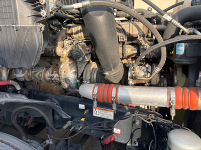 Inline view of a Freightliner PT126064ST engine bay showing intake piping, turbocharger, hoses, and a red-and-silver insulated exhaust/hard line.
