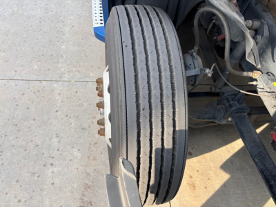 Front axle view of Freightliner PT126064ST showing dual wheels and dual drive tires with exposed suspension and brake components.