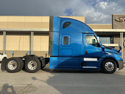 Side view of blue Freightliner PT126064ST tractor-trailer showing cab and rear wheels.