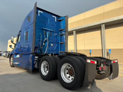 Freightliner PT126064ST truck tractor rear and side view showing tandem axles and sleeper cab in blue with dual rear wheels and mud flaps.
