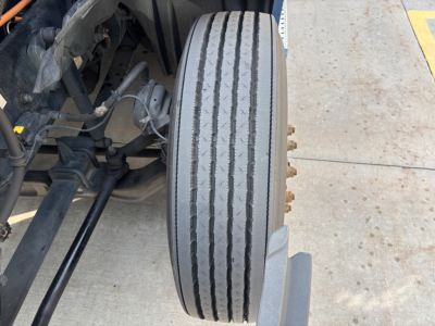 Front dual-axle truck wheel/view of tire with label details and suspension components; no legible stickers visible in this crop.