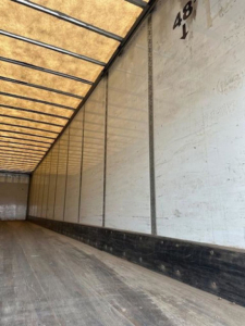 Trailer interior of a 2016 Wabash van with wooden floor and white side walls, rear door tracks, cargo area seen, markings on wall.