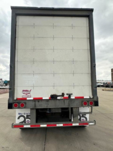 Rear view of a 2016 Wabash van trailer showing back doors, bumper, and lights with VIN and stock sticker area visible.