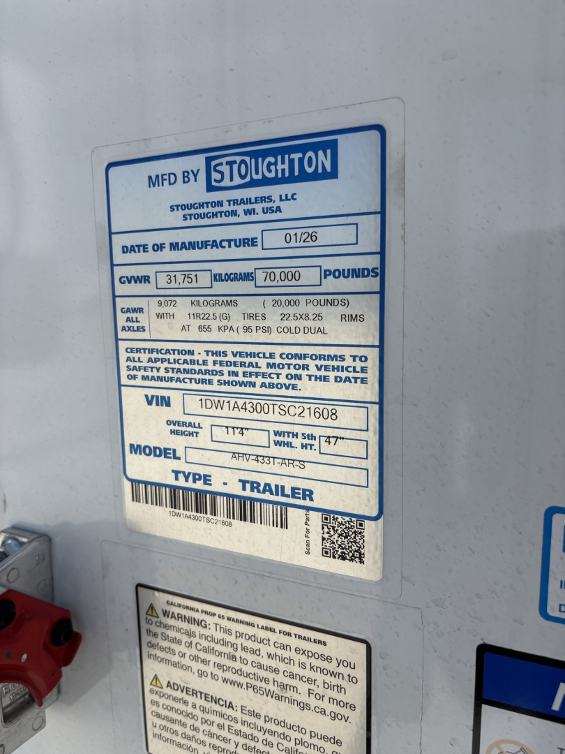 Trailer side showing a blue and white label with MFD BY STOUGHTON and VIN 1DW1A4300TSC21608, GVWR 70,000 lbs, GAWR 35,751 kg, model and type trailer.