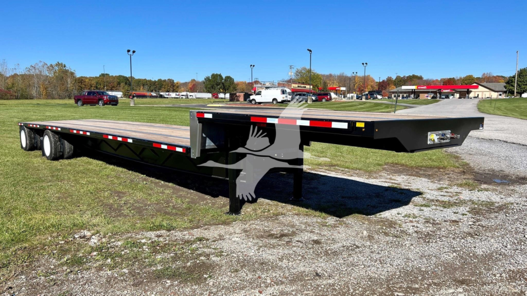 Transcraft drop deck trailer showing long low-profile flatbed with tapering gooseneck and dual rear axles.