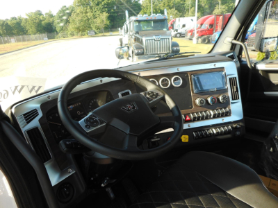 Interior of a Western Star 49X truck cabin showing steering wheel, dashboard with gauges, infotainment screen, climate controls, and gear shifter.