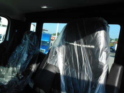New Western Star 49X day cab interior view with plastic-covered seats and dashboard; visible window showing parking lot.