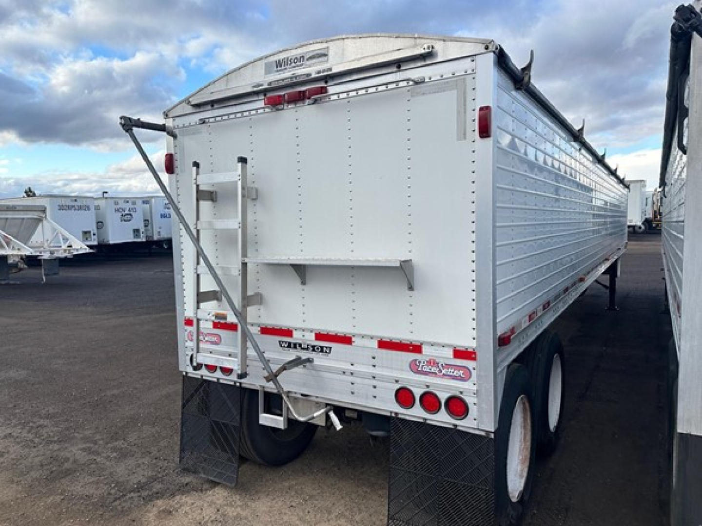 Gooseneck Wilson Pacesetter hopper trailer back view showing twin axles and rear bumper with lights.