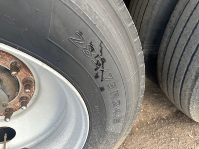 Tire sidewall with size marking 225/75R25 showing wheel hub and lug nuts on a trailer.