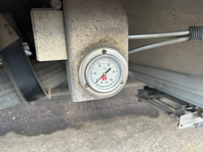Gauge on trailer hitch showing tire pressure/Load? meter with circular dial. No legible brand text visible.