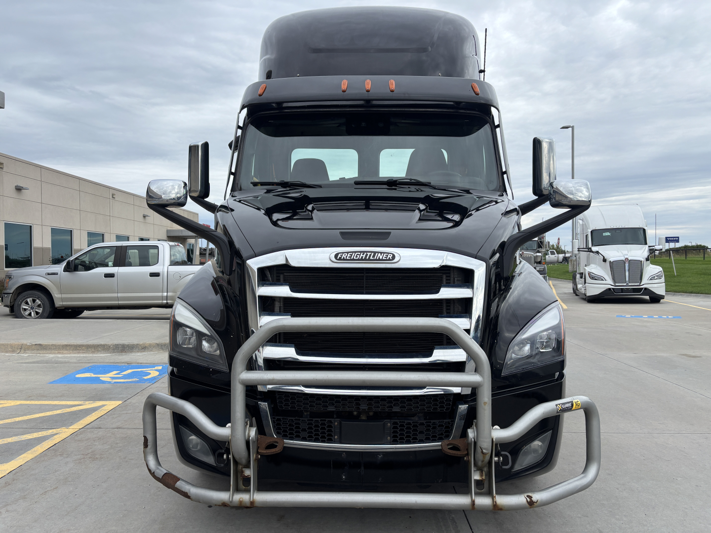 Freightliner truck front view showing bull bar and grille with PE11664DC label, black cab, chrome mirrors and headlights.