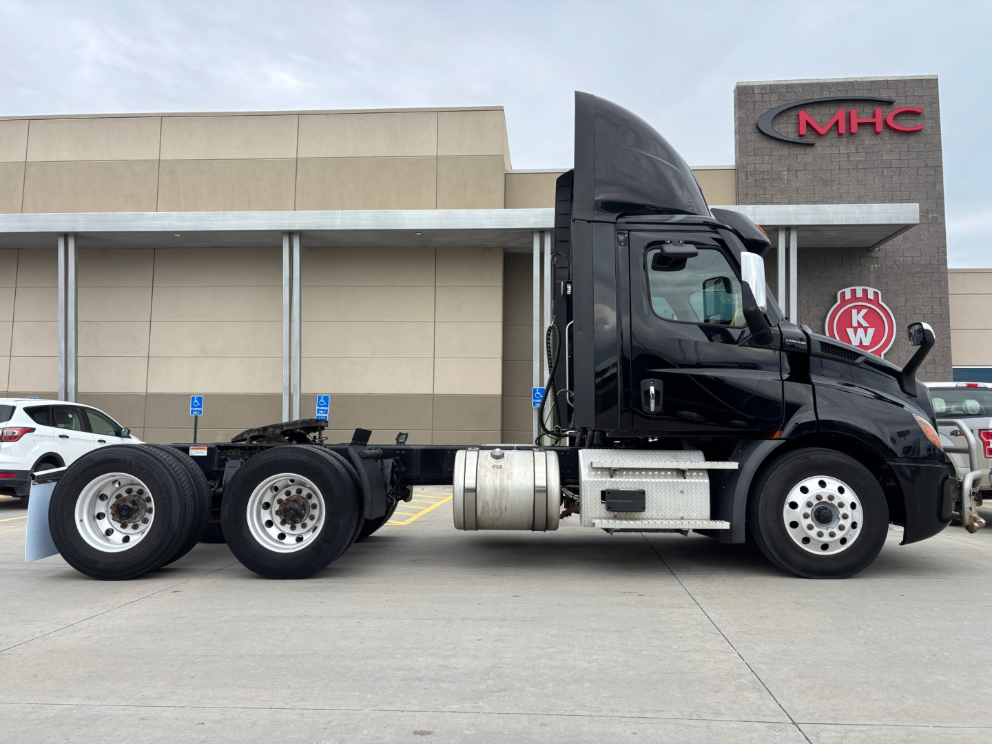 Truck side view showing Freightliner cab and chassis with three rear axles, fuel tank, and exhaust visible in year 2023 Freightliner PE11664DC listing.
