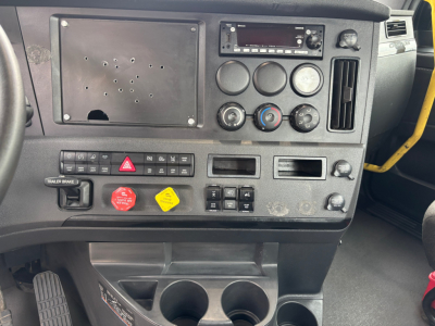 Dashboard of a Freightliner truck interior with circular knobs, radio, hazard switch, and cup holders visible; VIN and stock info not shown in image.