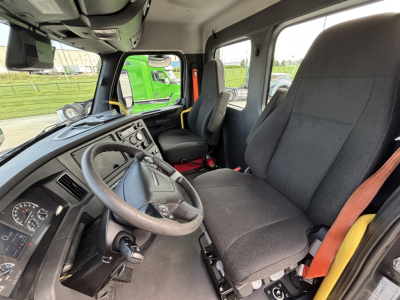 Truck cab interior showing steering wheel, dashboard, driver seat, and passenger seat in a Freightliner daycab.