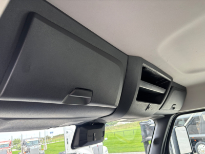 Cab interior showing overhead console and sun visor area with storage compartment and air vent in a Freightliner truck cab.