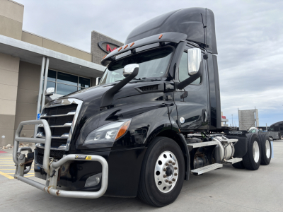 Freightliner conventional daycab tractor showing front grille guard and large chrome bumper with bumper guard and dual rear wheels.
