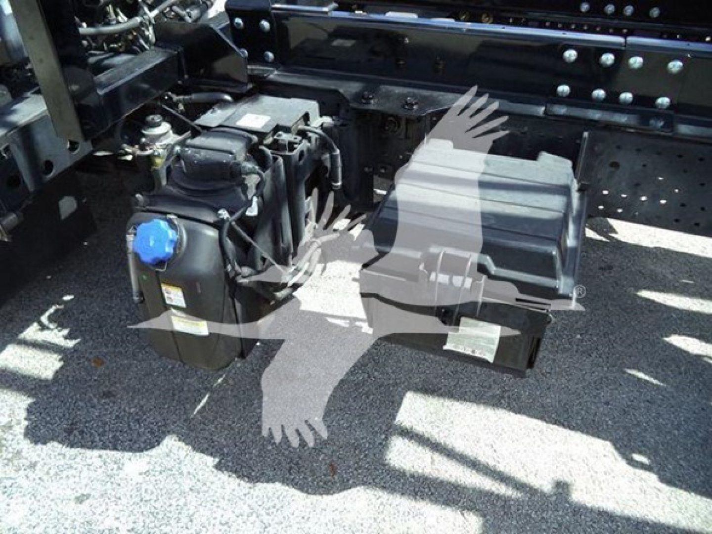 Isuzu NRR chassis view showing air intake/filters and auxiliary components under the cab with blue cap on fluid reservoir