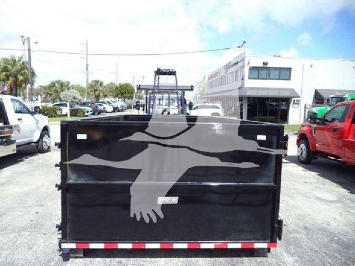 Isuzu NRR dump truck bed showing black dump body with rear hinge, reflective red-white safety stripe, and drop tailgate.