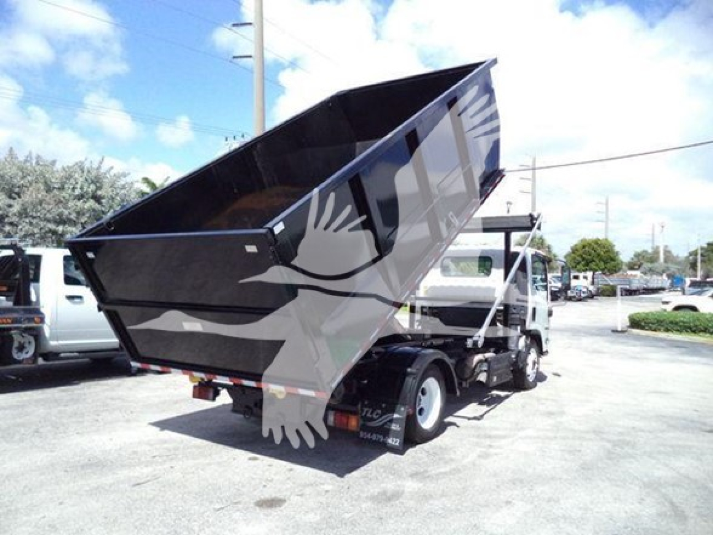 Isuzu NRR dump truck (rolloff) side view showing large open-top dump bed raised upward.