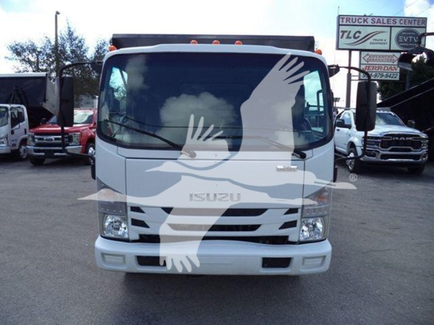 Isuzu NRR truck front view in dealership lot showing Isuzu emblem and grille with windshield and side mirrors.