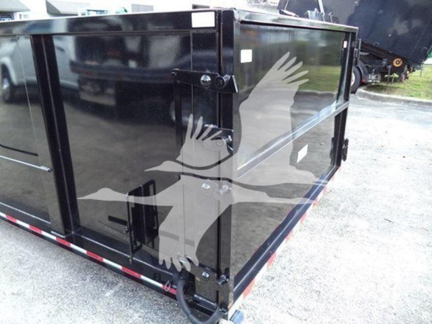 Isuzu NRR rolloff truck bed side view showing black painted steel container with hinges and latch.