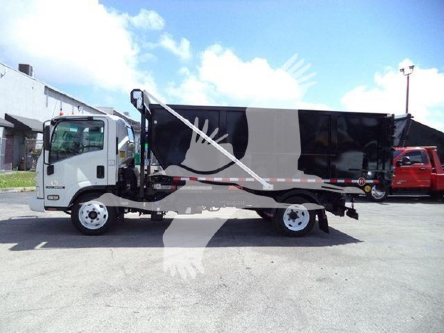 Isuzu NRR roll-off truck in-service showing side view with dump body and wheels.