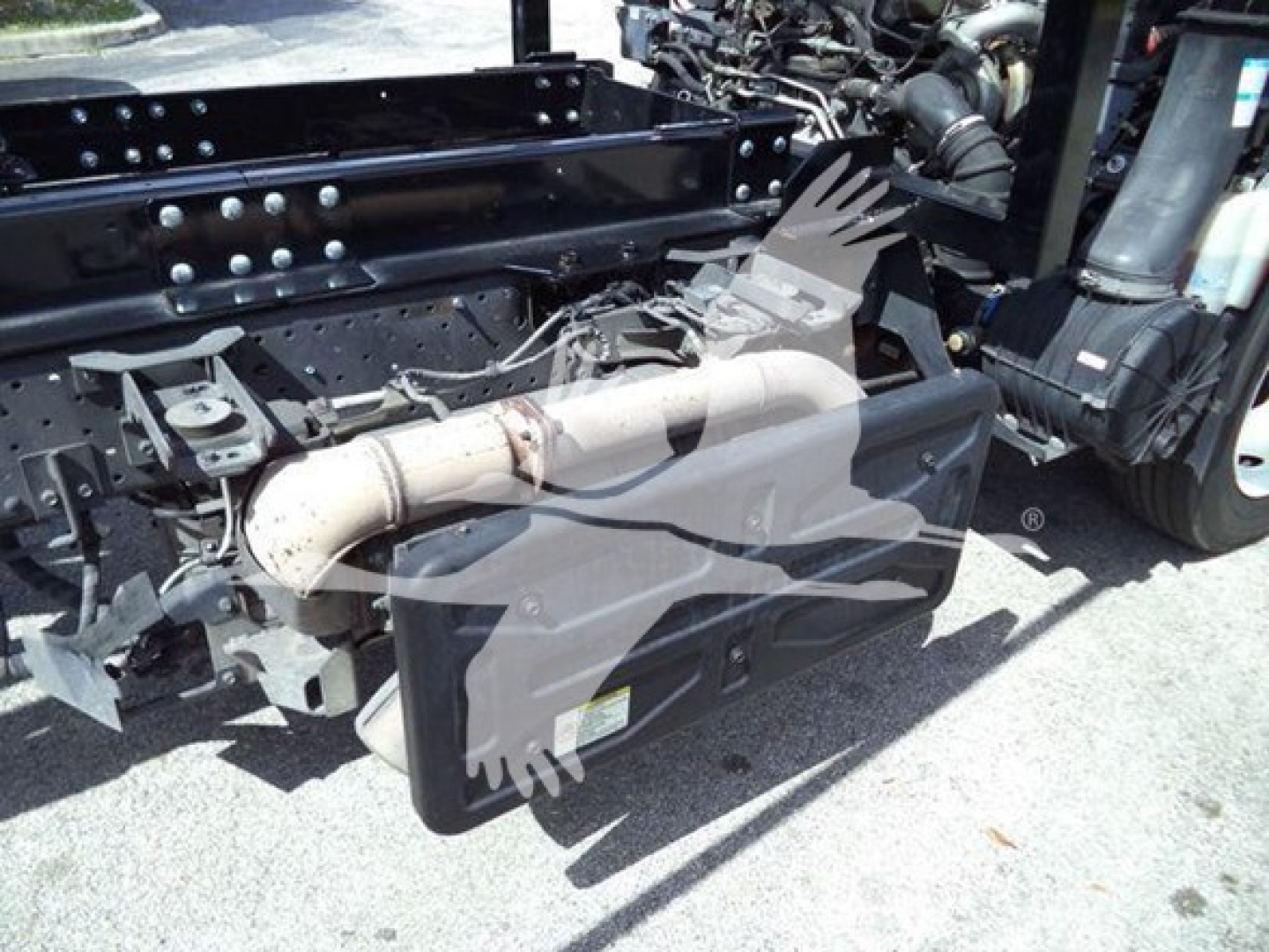Isuzu NRR truck chassis with diesel exhaust aftertreatment and undercarriage components visible, including exhaust pipe and suspension; side view of frame and cab connection.