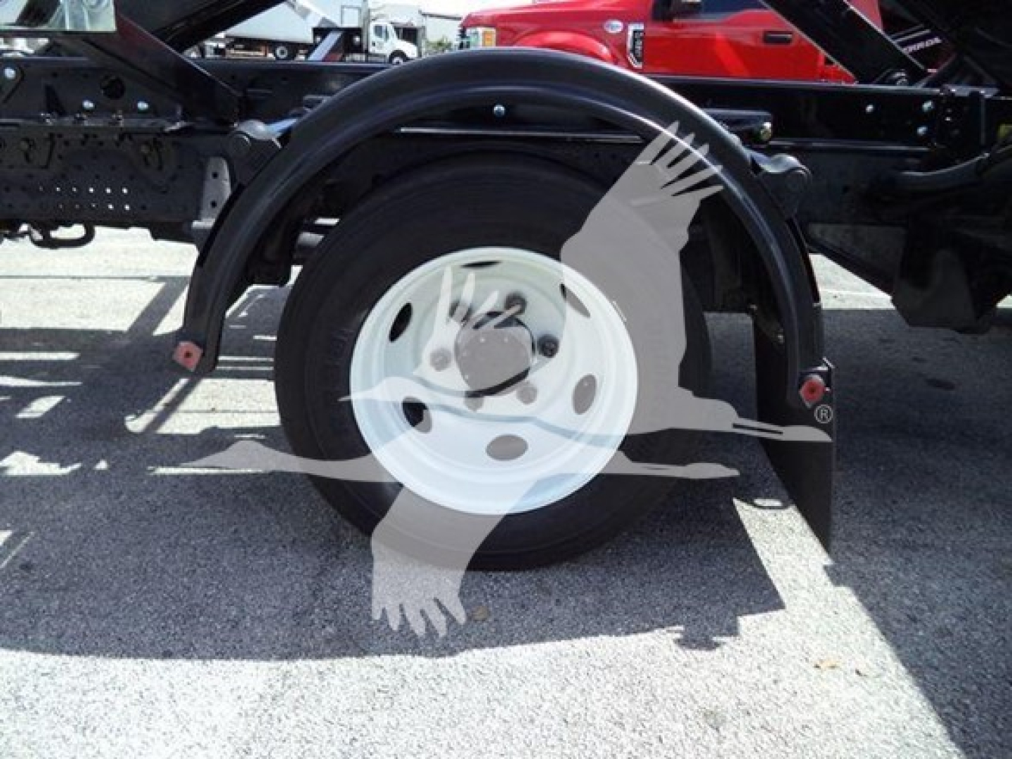 Isuzu NRR wheel and fender view showing front half of cargo chassis with circular white rim and black tire.
