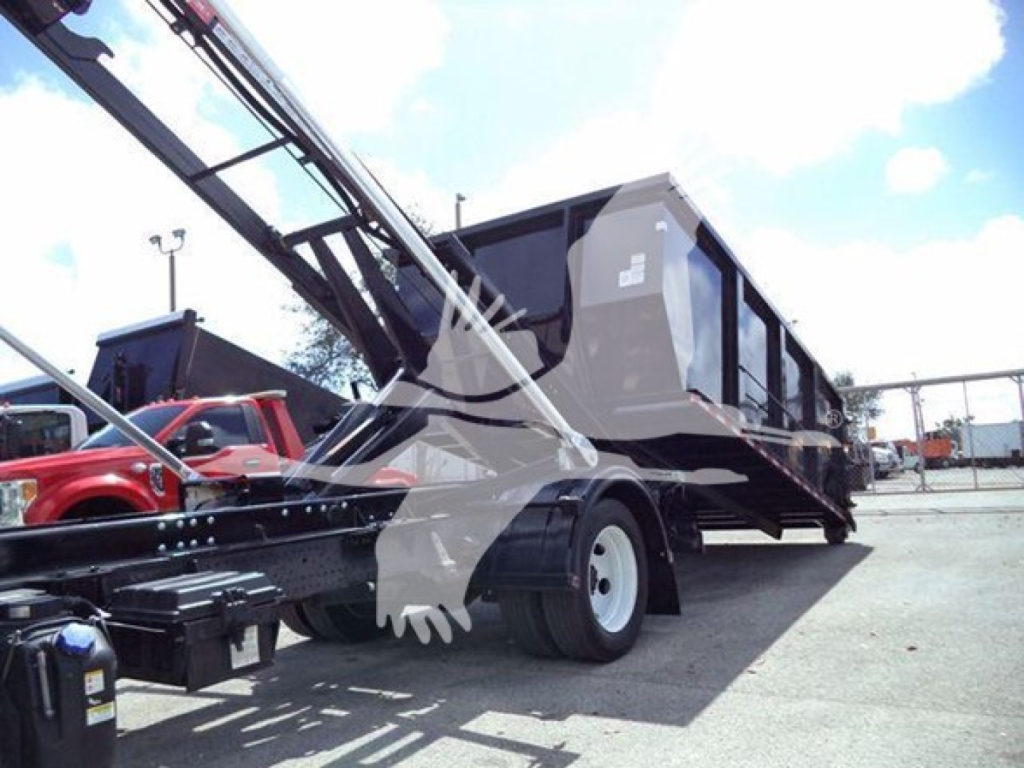 Isuzu NRR roll-off truck with suspended container and hydraulic crane arm in position, side view showing chassis and rear wheels.