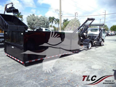 Isuzu NRR truck with a large black roll-off container and a crane/loader in a parking lot.