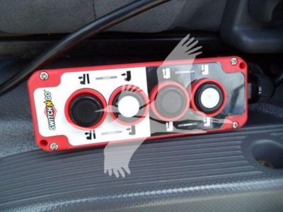 Isuzu NPR/NRR control panel with four circular buttons and switches in red housing, mounted on a vehicle interior step area.