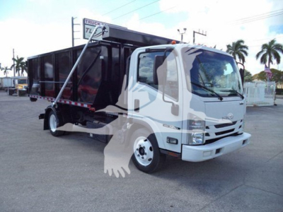 Isuzu NPR/NQR style cab over truck with a black dump bed in a yard