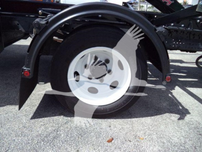 Isuzu NRR roll-off truck rear wheel and fender showing white steel wheel, black fender, and surrounding chassis components.