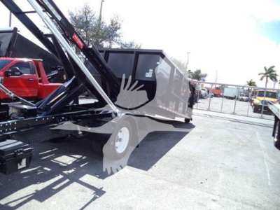 Isuzu NRR roll-off truck with hydraulic arm and grey dumpster on bed, side view showing rear chassis.