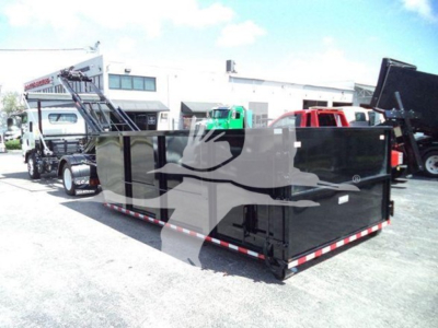 Isuzu truck in a lot with a large black rollover container trailer attached, multiple vehicles in background.