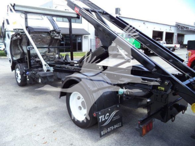 Isuzu NRR roll-off truck rear view showing hydraulic hoist and chassis with TLC logo and contact number; mid-section of cab removed, VIN and stock details not visible in text.