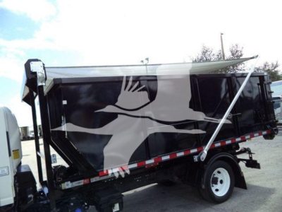 Isuzu NRR roll-off truck with a black dump body, logo on side, and hydraulic tarp/cover in raised position.