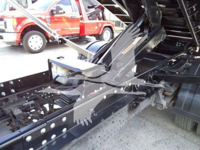 Isuzu NRR roll-off truck chassis with hydraulic components and metal framework visible in the bed area.