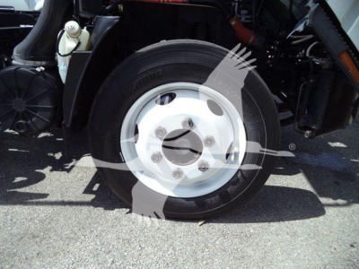 Isuzu NRR wheel/tender area showing front tire and wheel with five lug nuts, part of truck undercarriage.