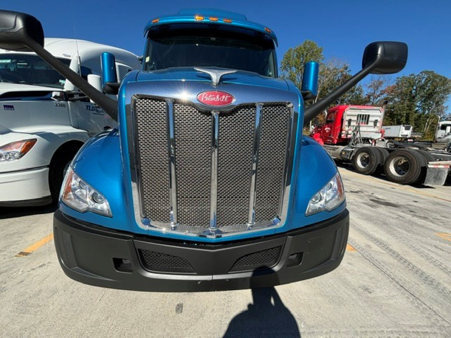Peterbilt 579 front view showing large chrome grille, blue cab, black bumper, and side mirrors.