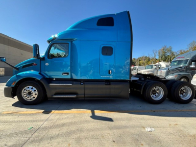 Peterbilt 579 in blue with sleeper cab, side view showing conventional truck, front grille, and dual rear axles.
