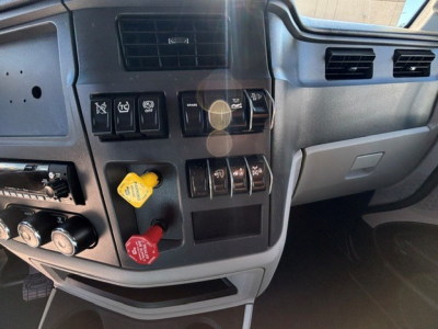 Truck cab interior dashboard of a 2022 Peterbilt 579 showing control switches, knobs, and yellow and red handles.