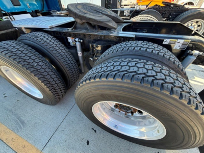 Peterbilt 579 truck chassis underside showing dual rear axles with pneumatic air bags and large treaded tires; chrome wheels; part of trailer hitch and frame visible