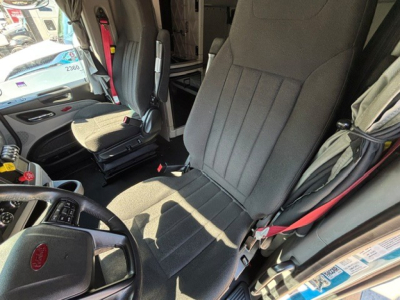 Peterbilt 579 truck interior showing driver seat and steering wheel with fabric seat and red seat belt in cabin.